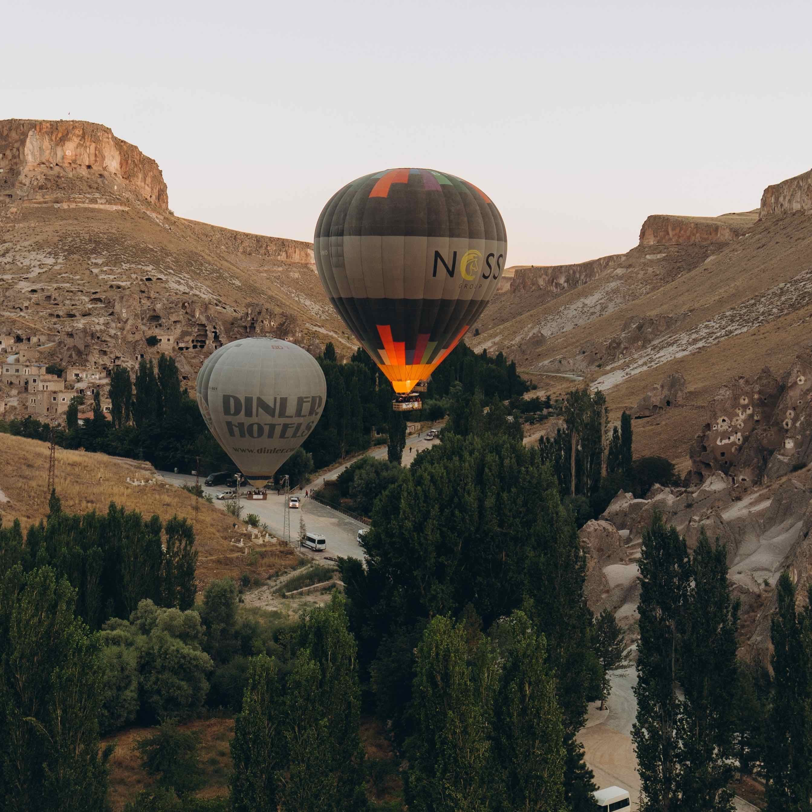 Hot air balloons flying low over the rock-hewn landscape of Soğanlı Valley